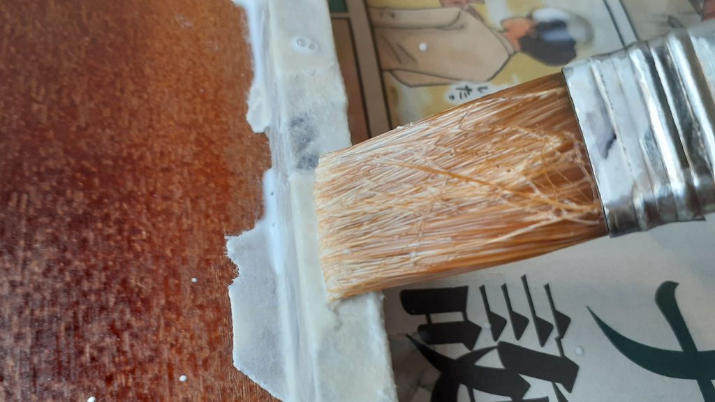 ちぎった半紙を木製お盆に貼っていく