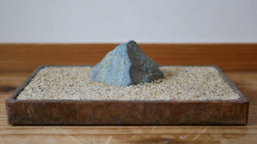 蒼黒の多摩川石を茶系贋水盤に飾ってみる